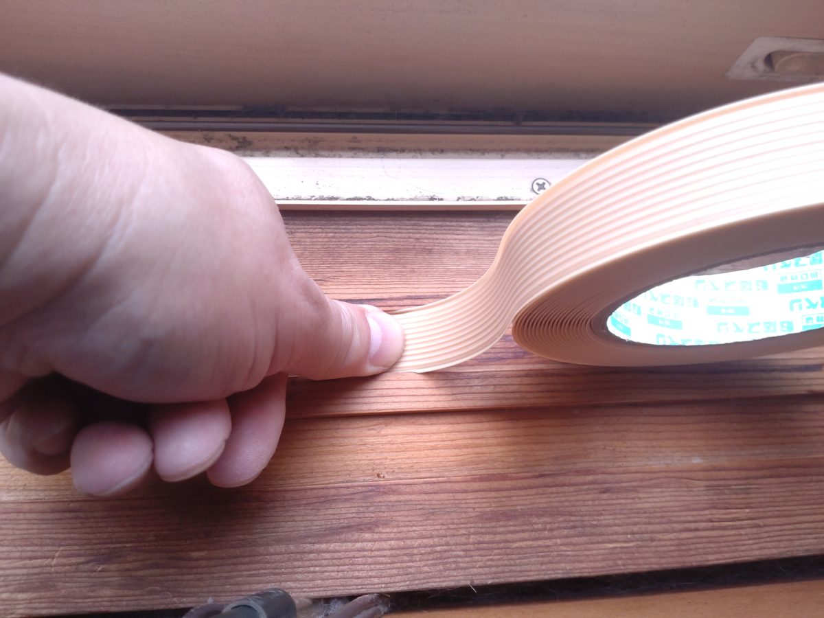 親指で敷居テープの端を押さえて貼り始めている